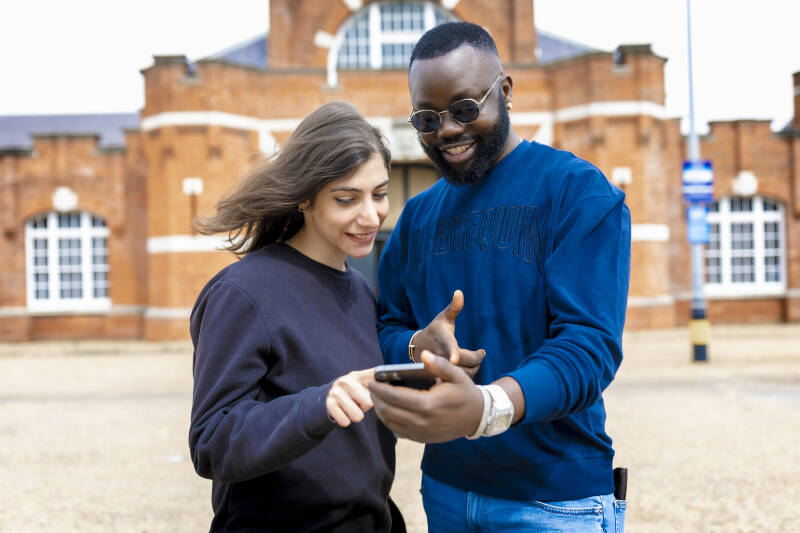Two students pointing at phone