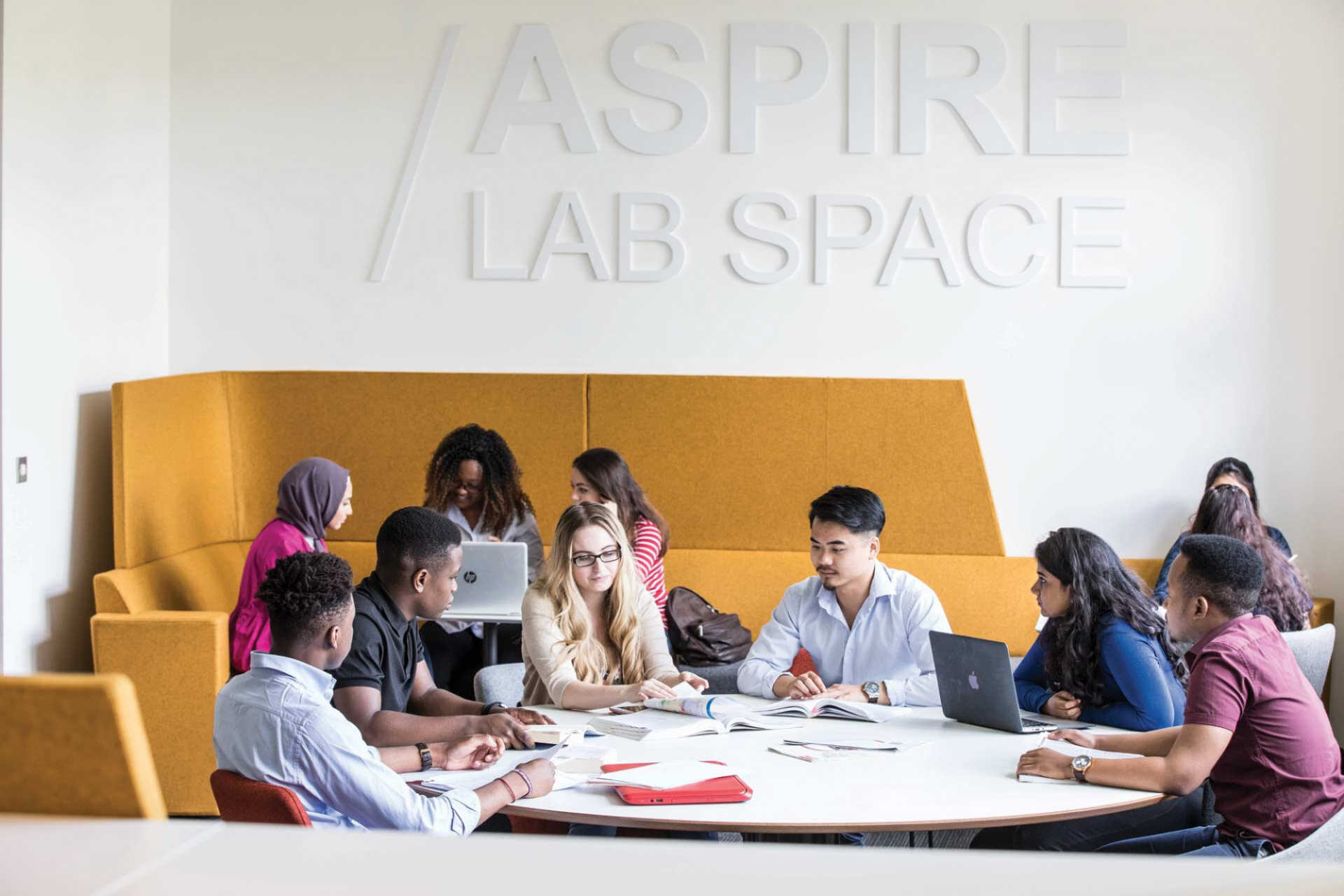 A group of postgraduates chat around a table in a Sibson Building study space