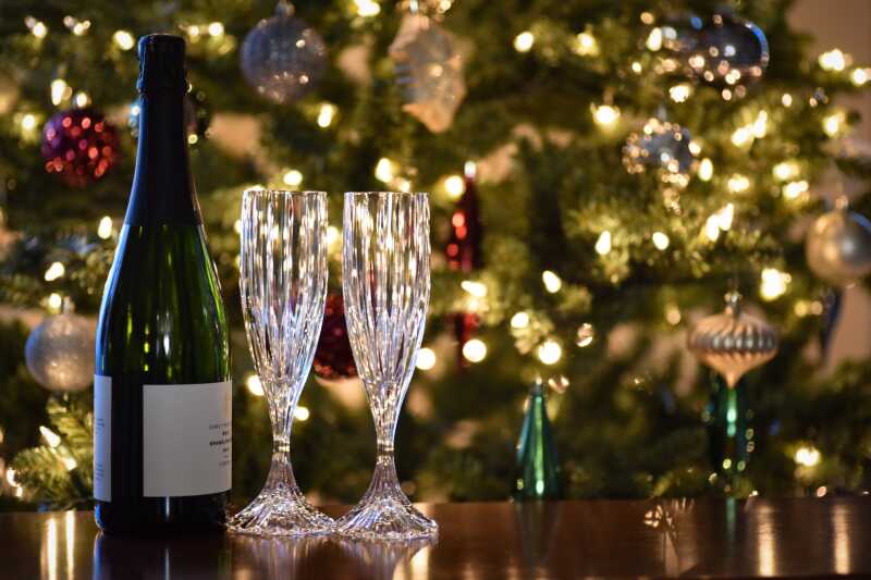 Bottle of champagne and glasses in front of a Christmas tree